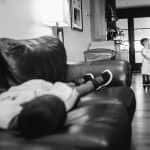 a black and white photo of a man and a child in a living room.