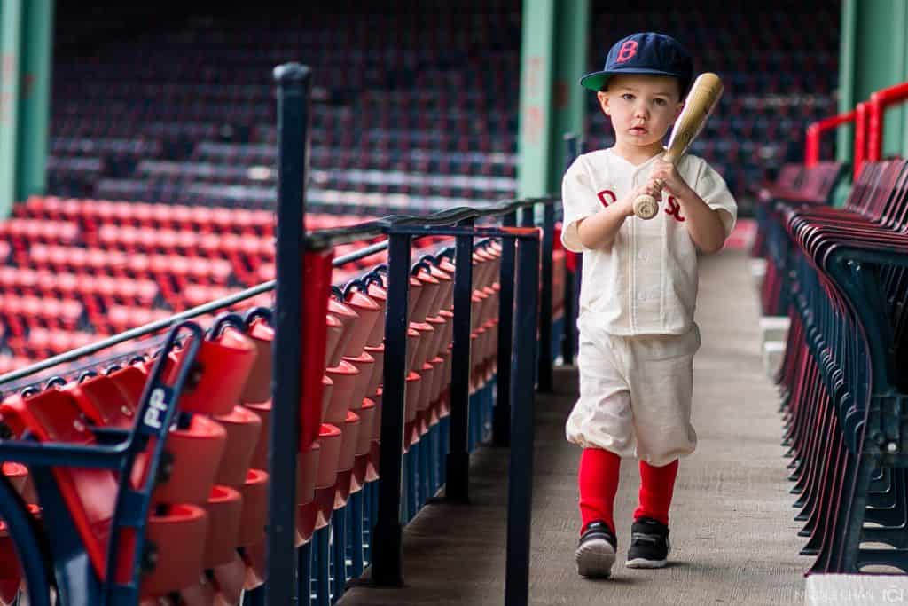 a young boy holding a baseball bat in a stadium.