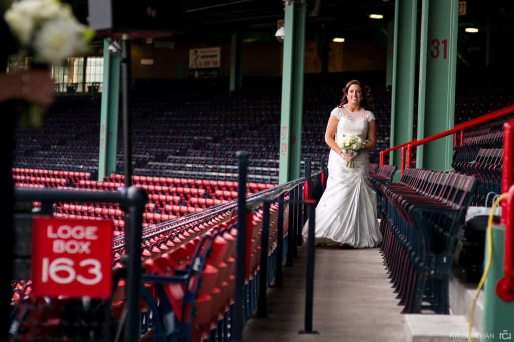 a woman in a wedding dress standing in a stadium.