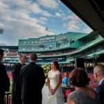 a bride and groom standing at the end of a baseball field.