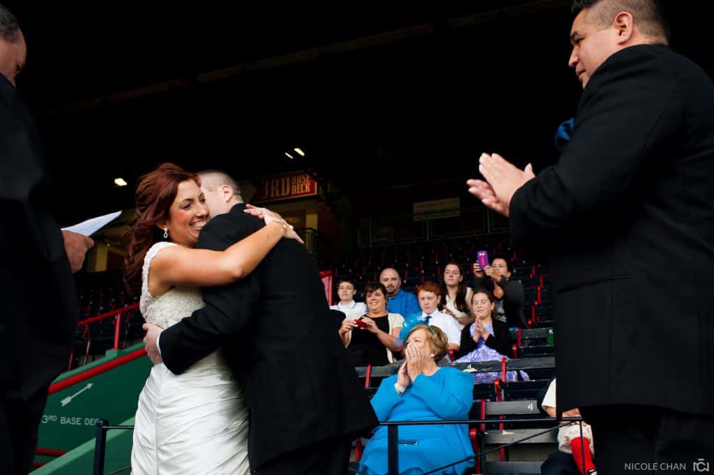 a bride and groom hug each other in front of a crowd.