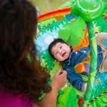 a woman is playing with a baby in a play mat.