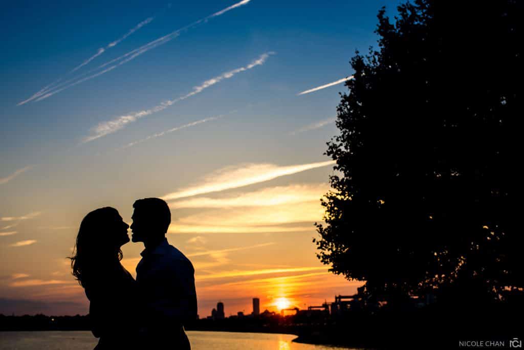 a man and woman standing next to each other at sunset.