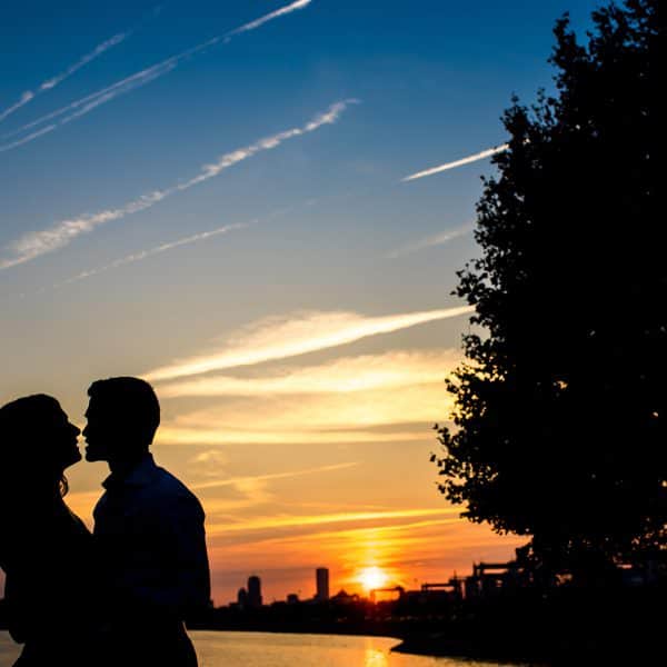 a man and woman standing next to each other at sunset.