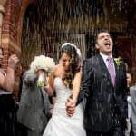 a bride and groom walking through the rain.