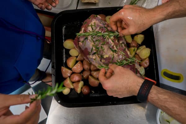 a man is putting a sprig of rosemary on a piece of meat.