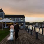 a bride and groom walking down a dock.