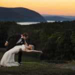 a bride and groom kissing in front of a sunset.