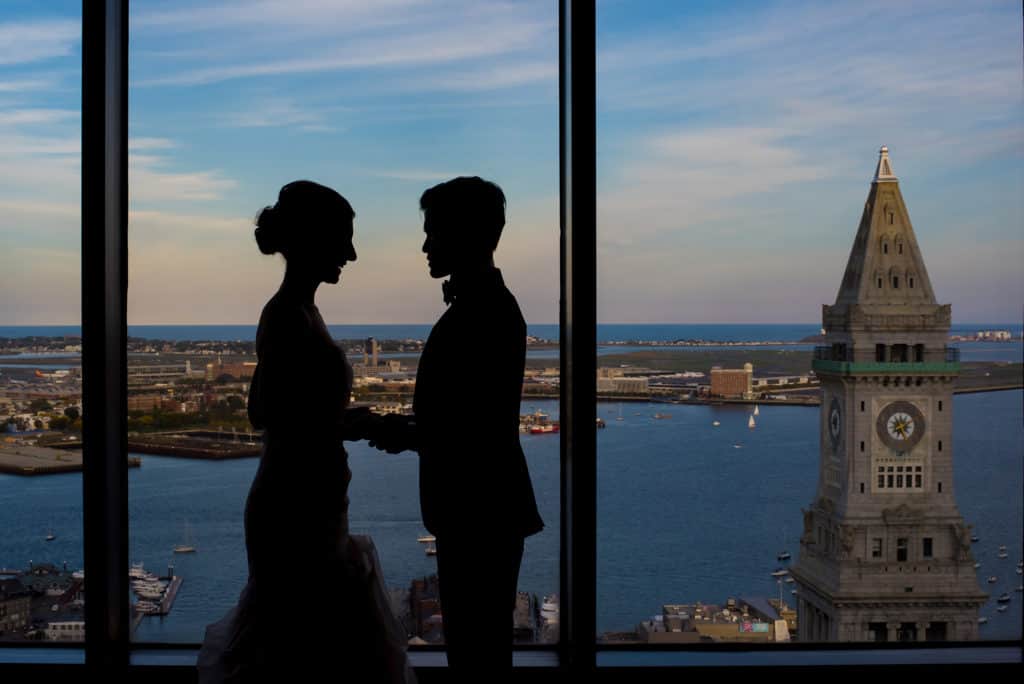 a bride and groom standing in front of a window.