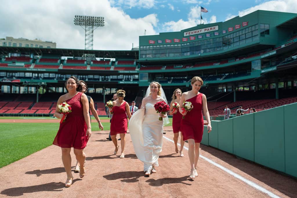 a bride and her bridesmaids walking down the field.
