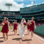a bride and her bridesmaids walking down the field.