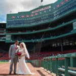 a bride and groom standing in front of a baseball stadium.