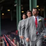 a group of men in suits walking down a baseball field.