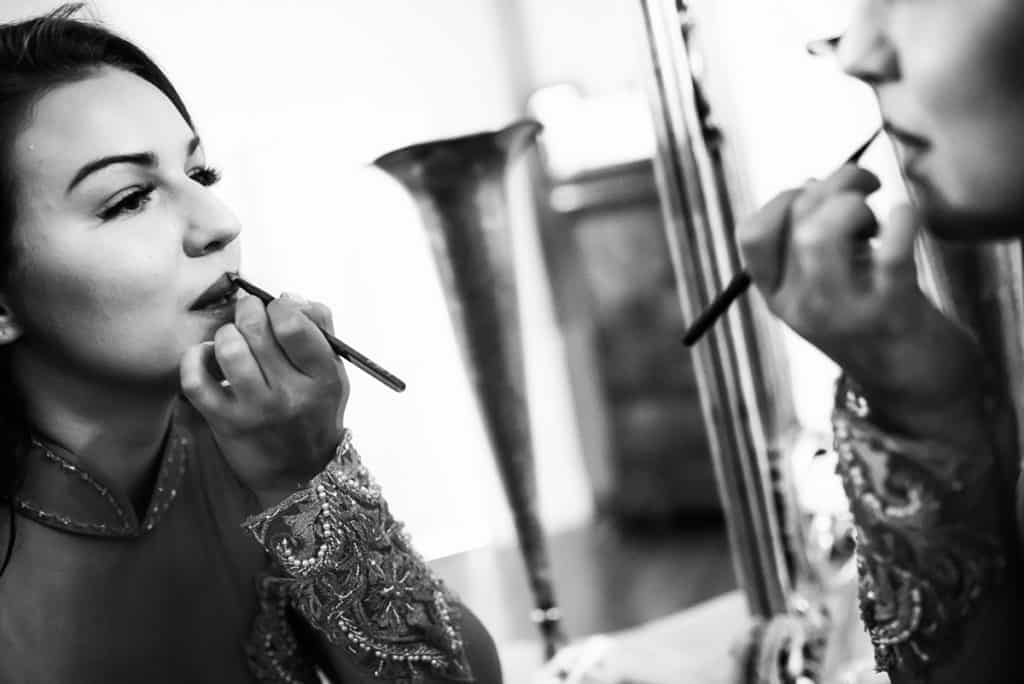 a woman is doing makeup in front of a mirror.