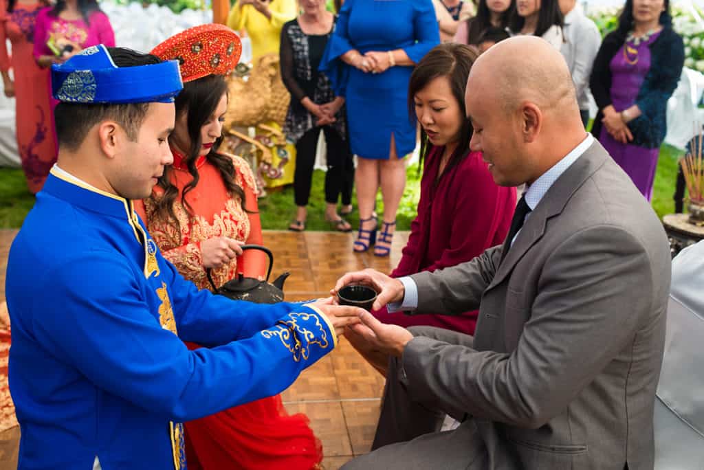 a man in a blue suit is handing something to a woman in a red dress.