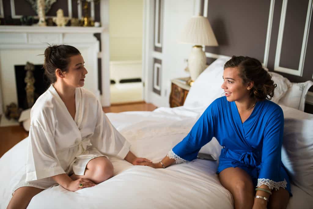 a couple of women sitting on top of a bed.
