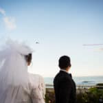 a bride and groom looking out at the ocean.