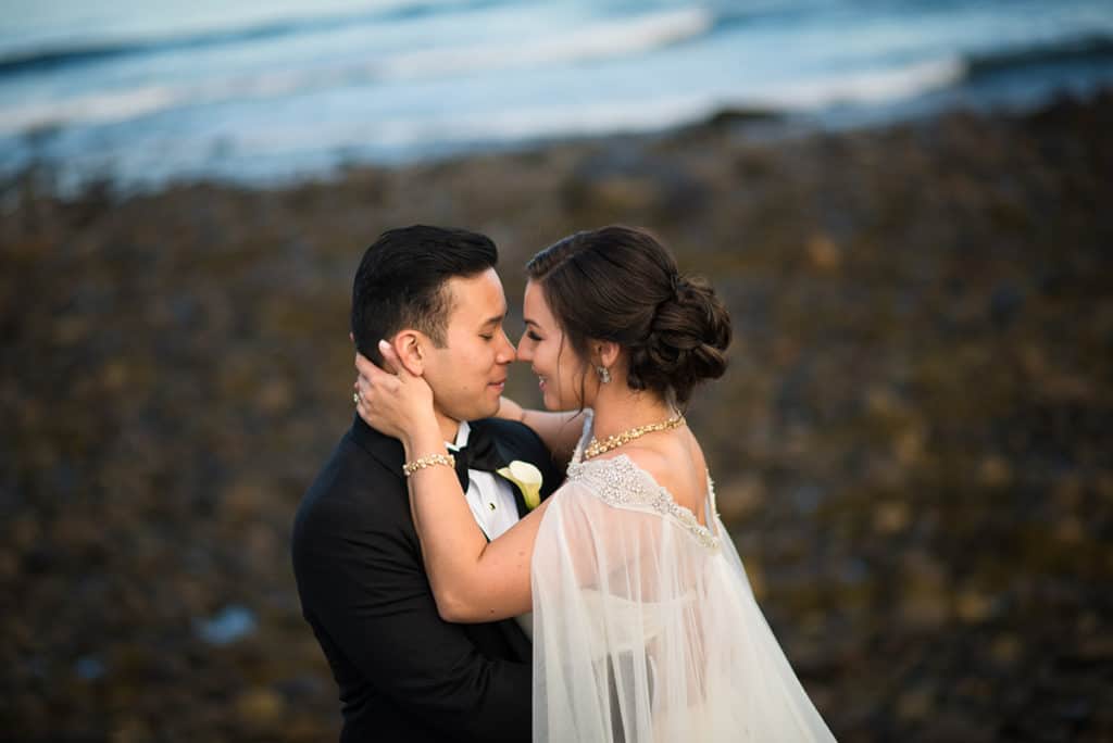a bride and groom embracing each other in front of the ocean.