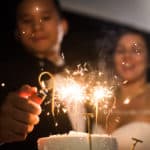 a bride and groom holding sparklers in front of a cake.
