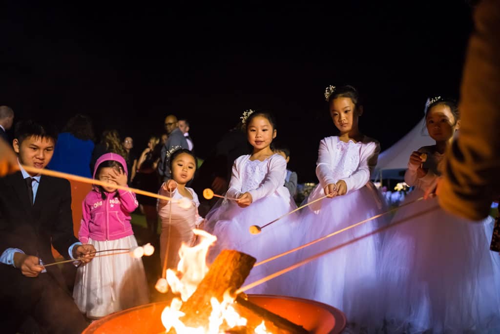 a group of children standing around a fire pit.