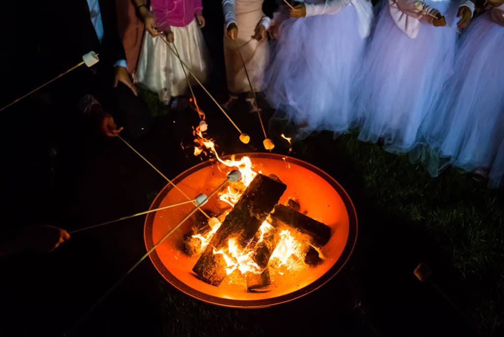 a group of people standing around a fire pit.