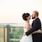 a bride and groom kissing on a balcony.