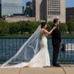 a bride and groom stand on a bridge overlooking the water.