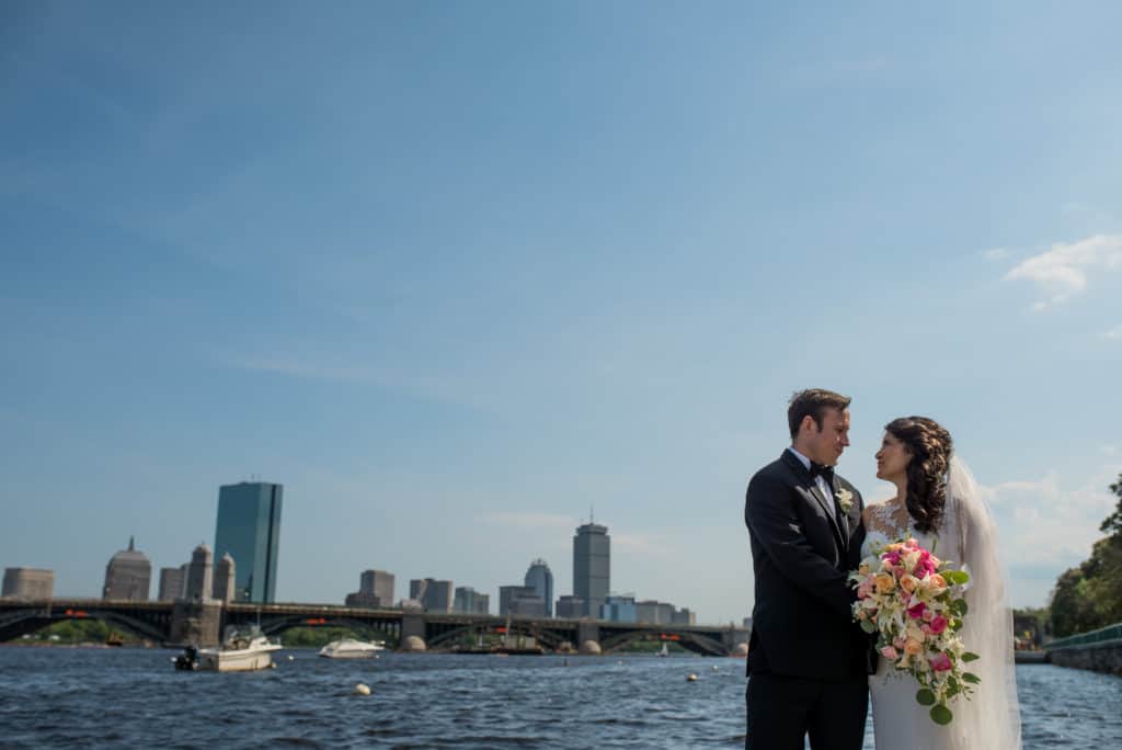 a bride and groom standing next to each other in front of a body of water.