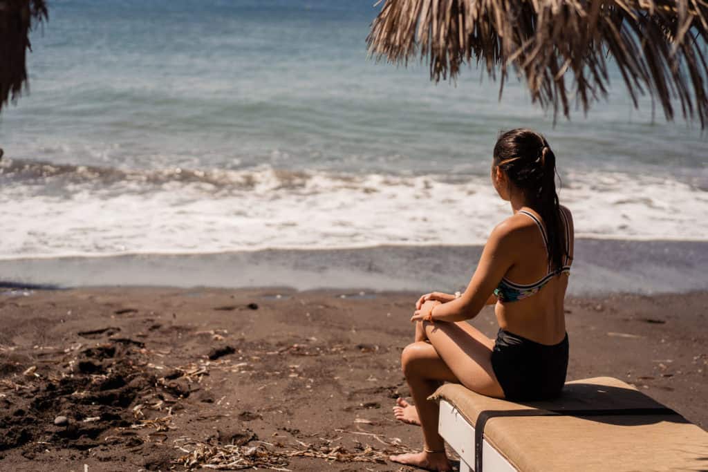 a woman sitting on top of a bench next to the ocean.