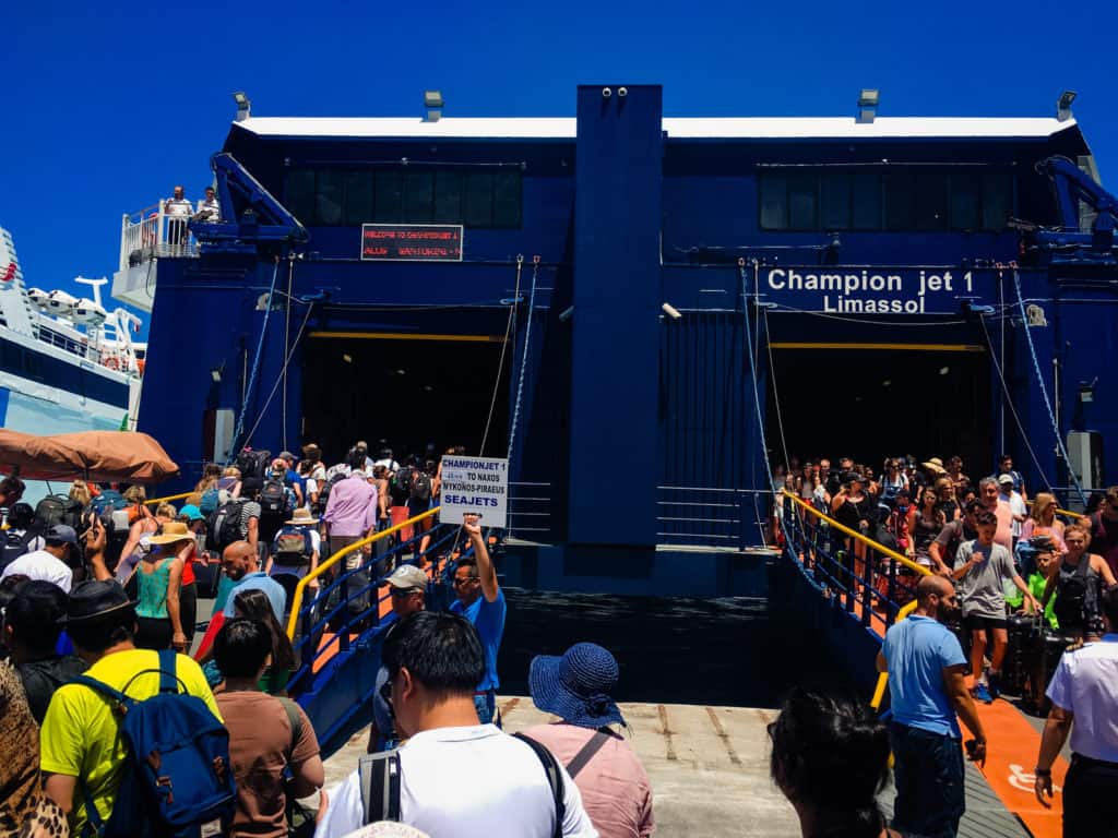 a large crowd of people waiting to board a ferry.