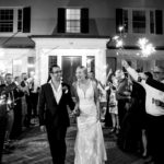 a bride and groom walking through a crowd of people holding sparklers.