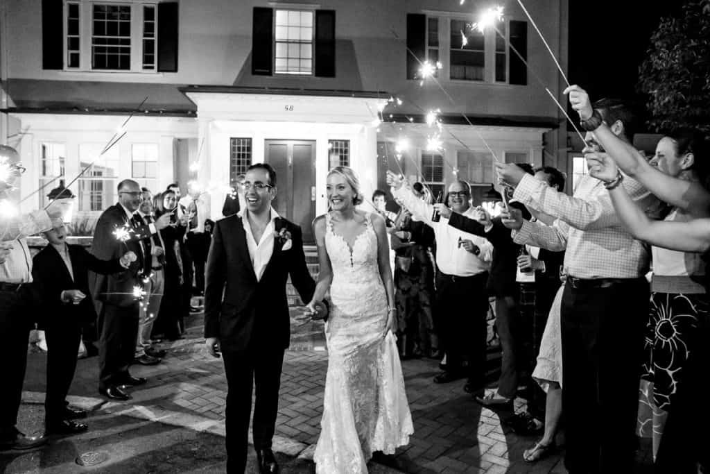 a bride and groom walk through a crowd of people holding sparklers.