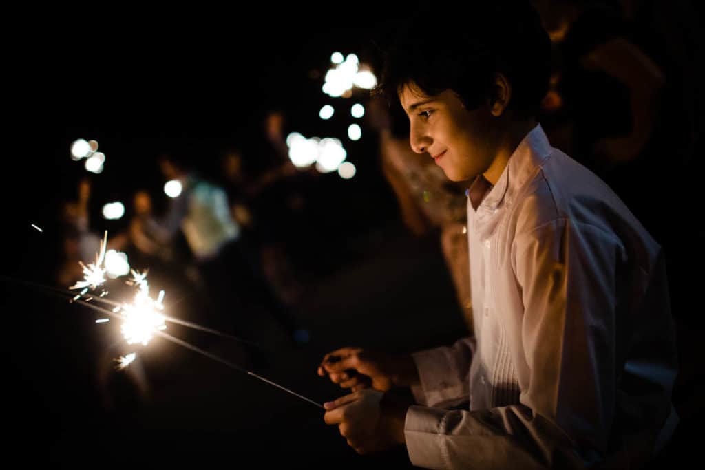 a young man holding a sparkler in his hand.