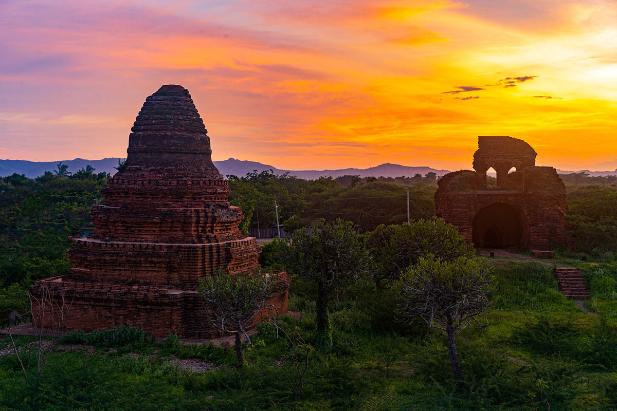 the sun is setting over the ruins of a temple.