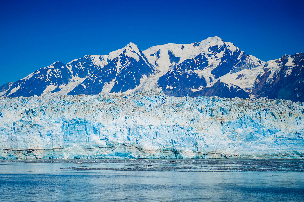 a large glacier with mountains in the background.
