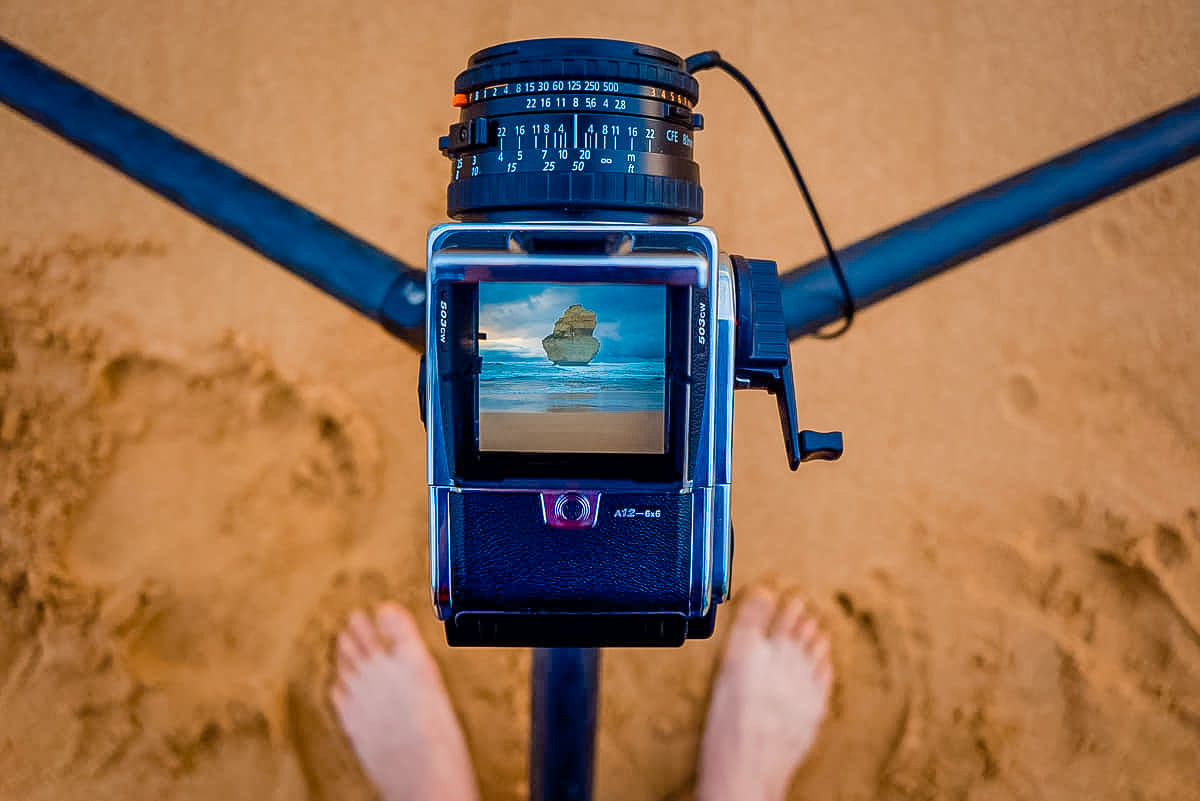 a person standing next to a camera on a beach.