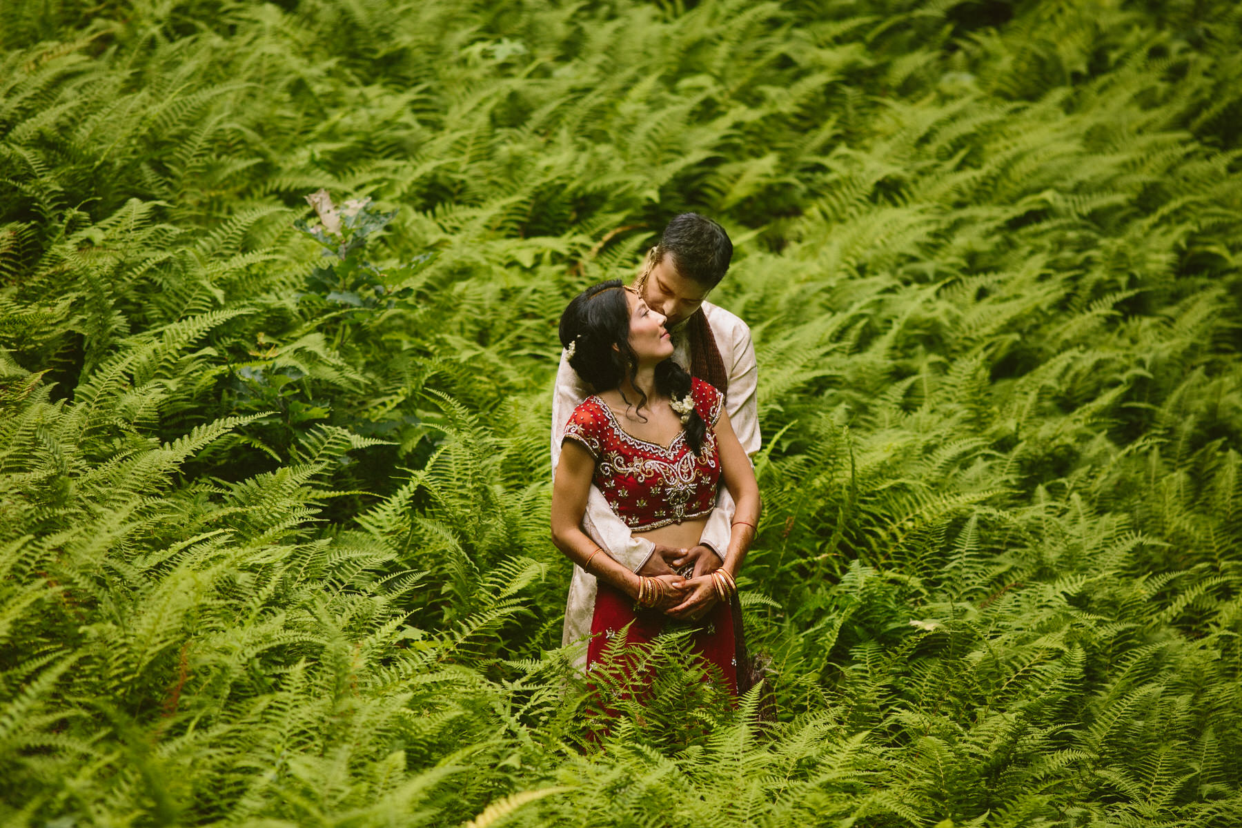 a man and a woman standing in a field of ferns.