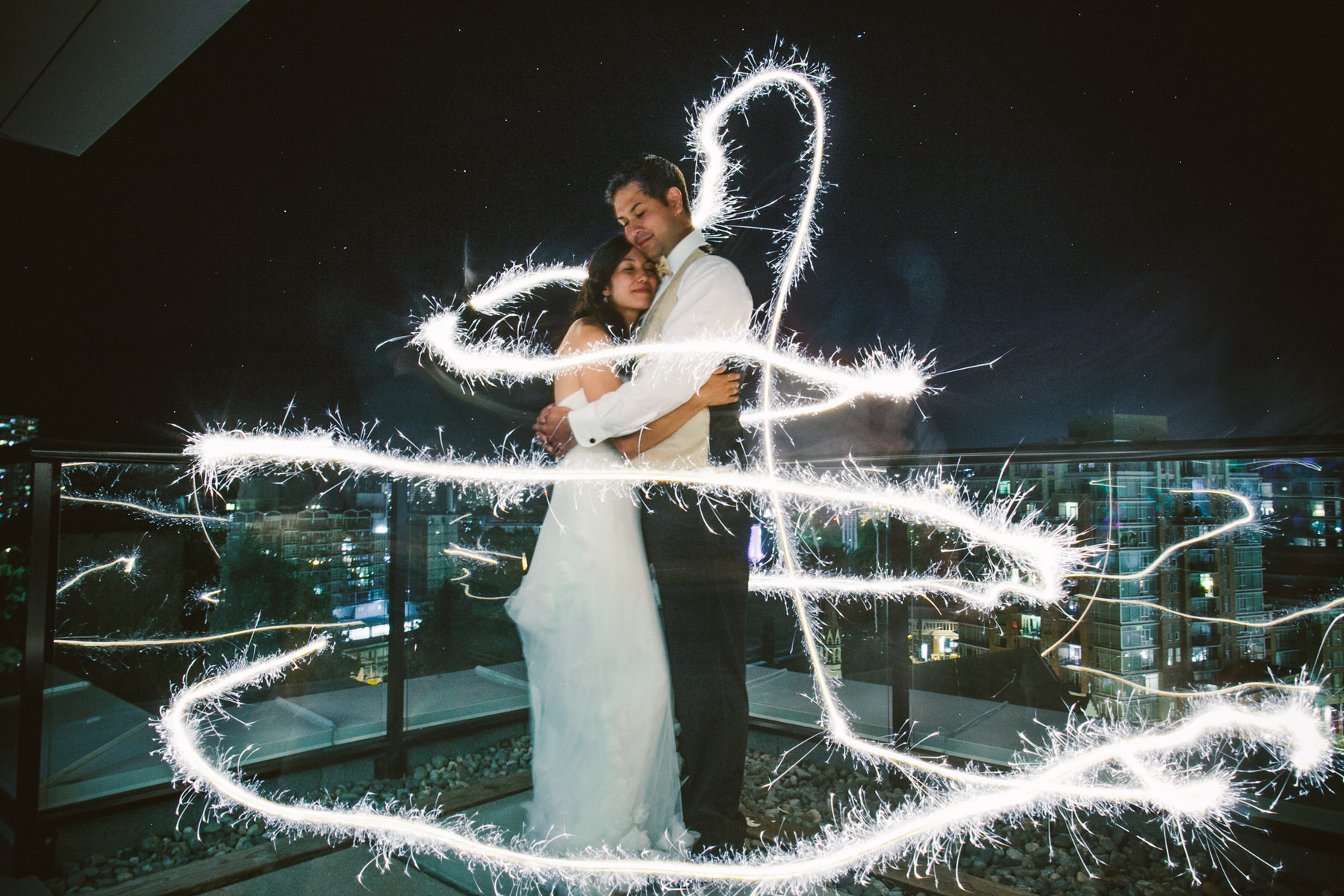 a bride and groom standing on a balcony with sparklers in the air.