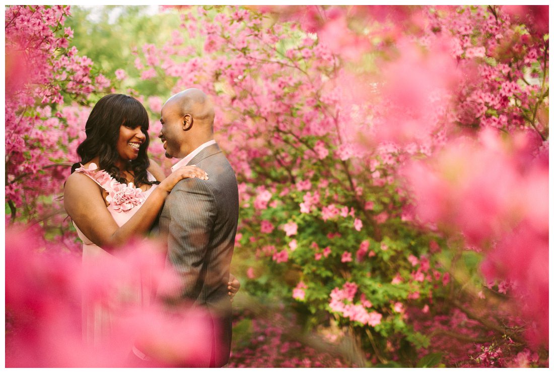 a man and woman standing in front of pink flowers.