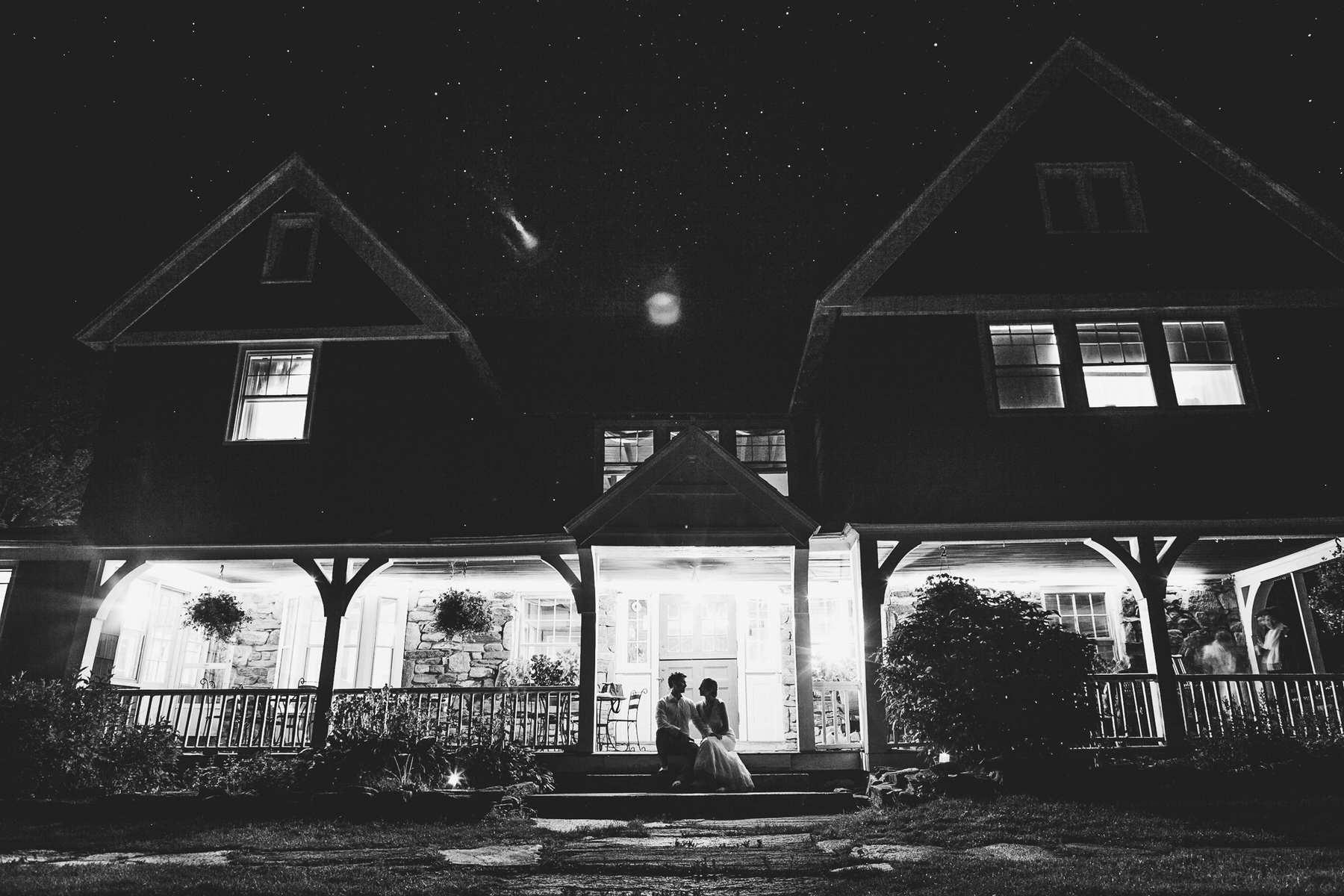 a couple standing in front of a house at night.