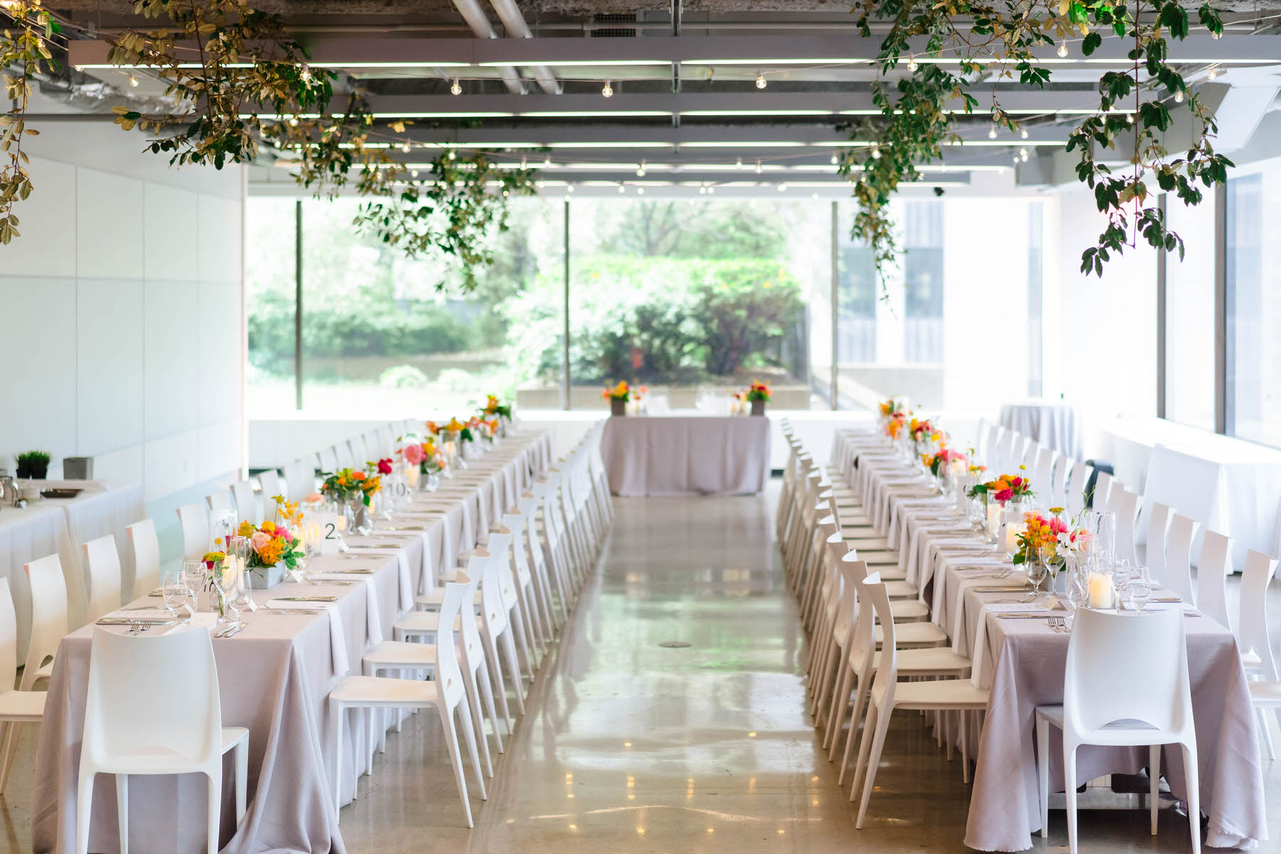 a long table with white chairs and white tablecloths.