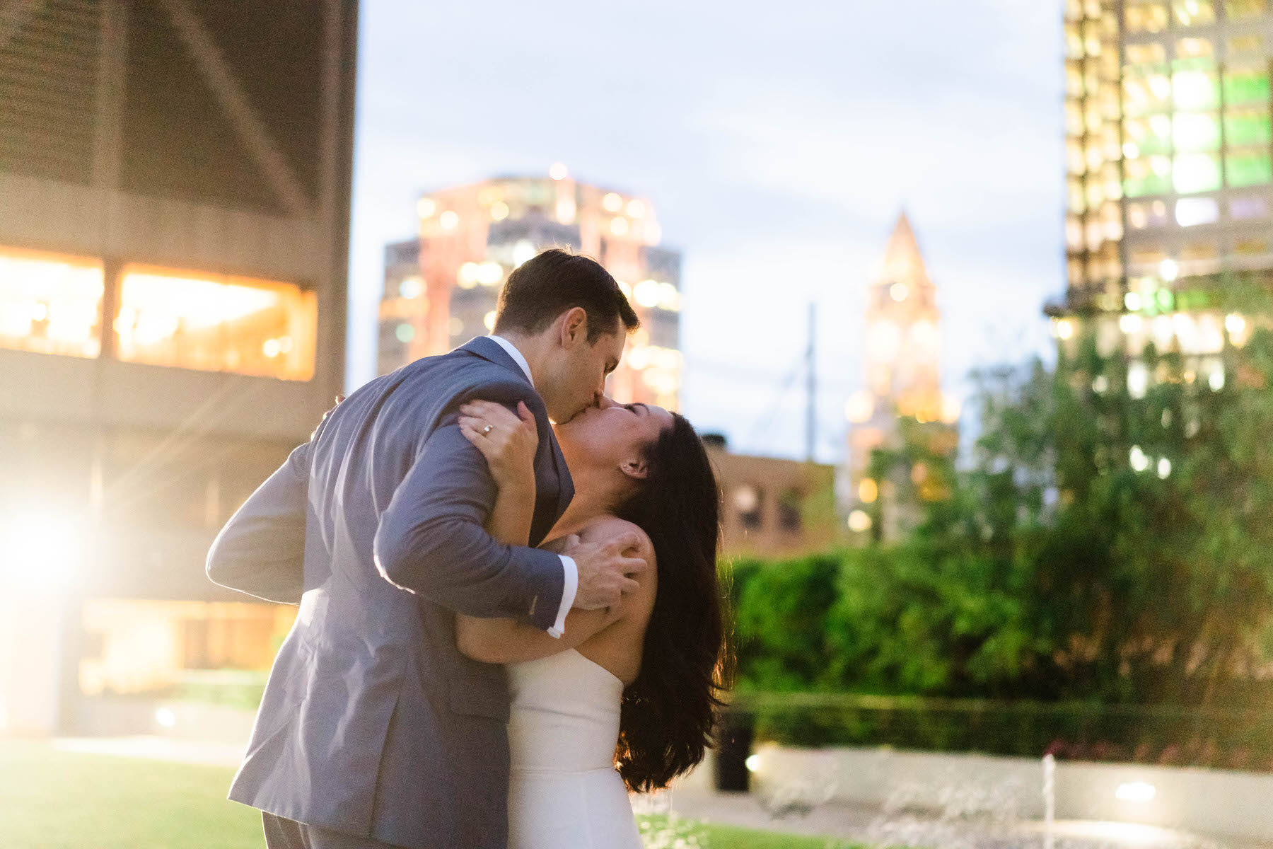 a bride and groom kissing in front of a cityscape.