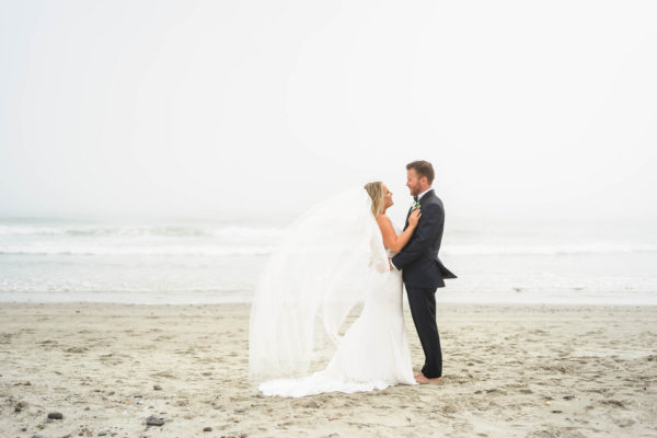a bride and groom standing on the beach.