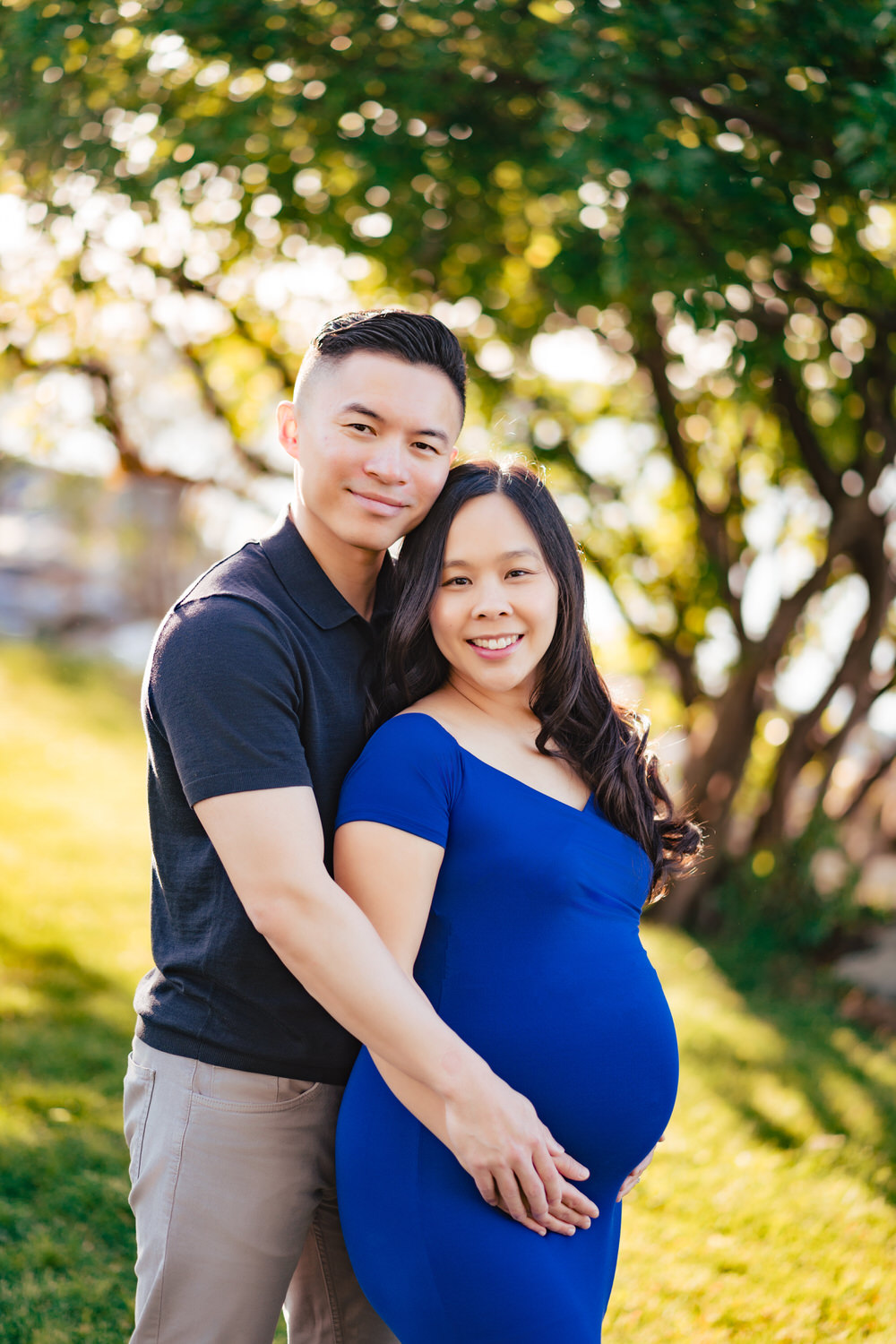 a pregnant couple posing for a picture in a park.