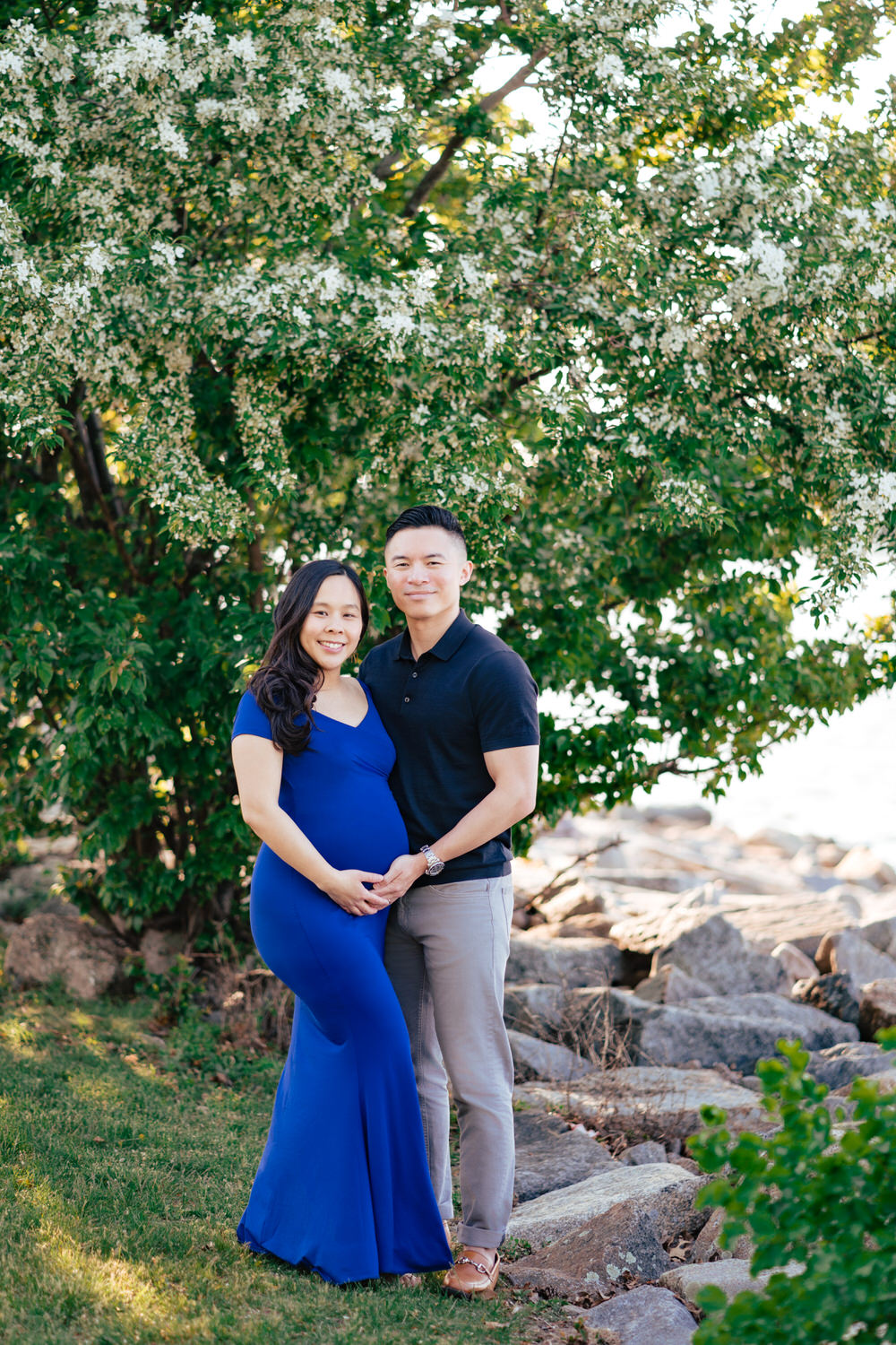 a pregnant couple standing in front of a tree.