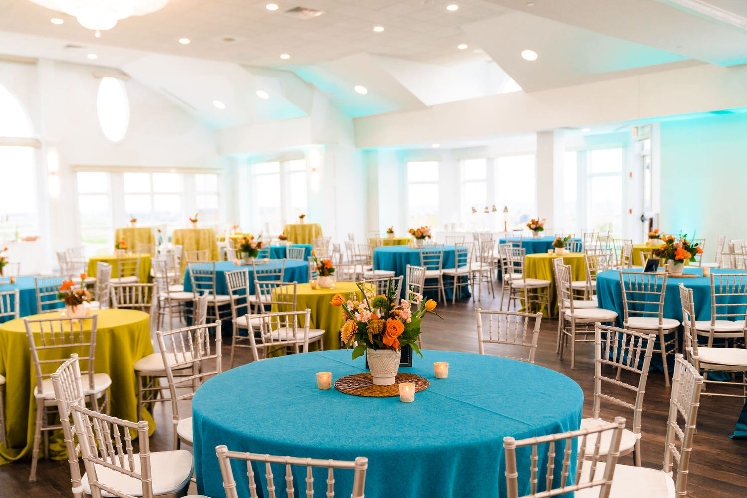 a room filled with lots of tables covered in blue and yellow cloths.