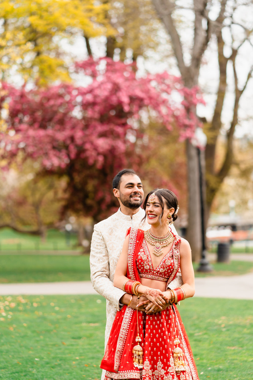 a bride and groom pose for a picture in a park.
