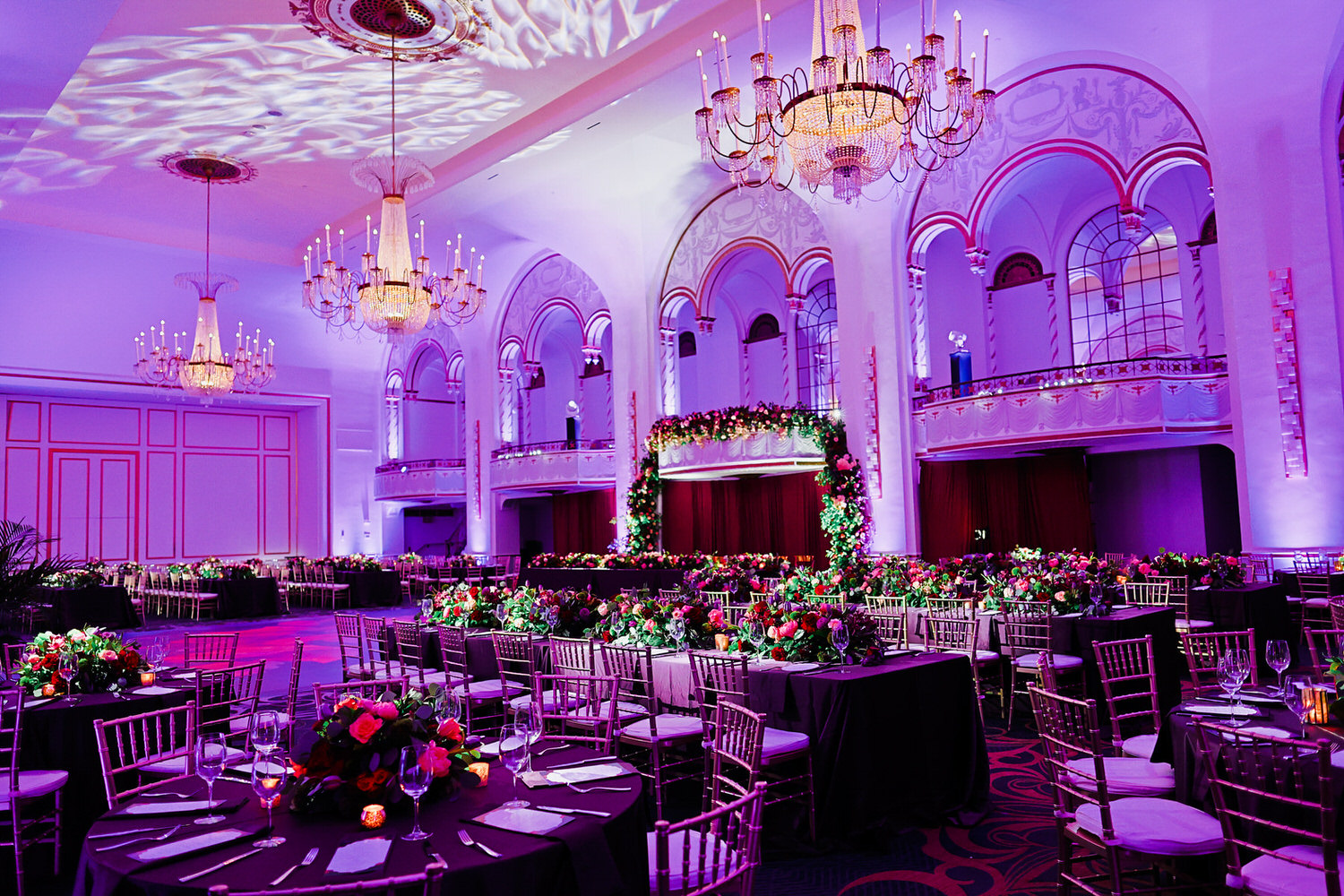 a banquet hall with tables, chairs, and chandeliers.