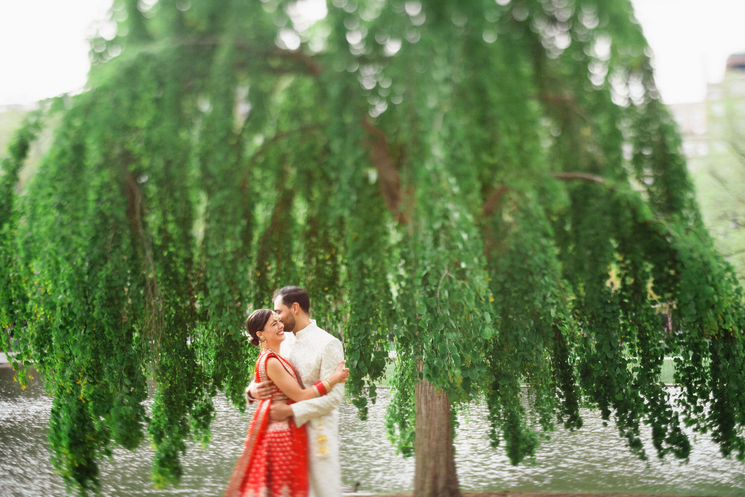 a bride and groom standing under a tree.