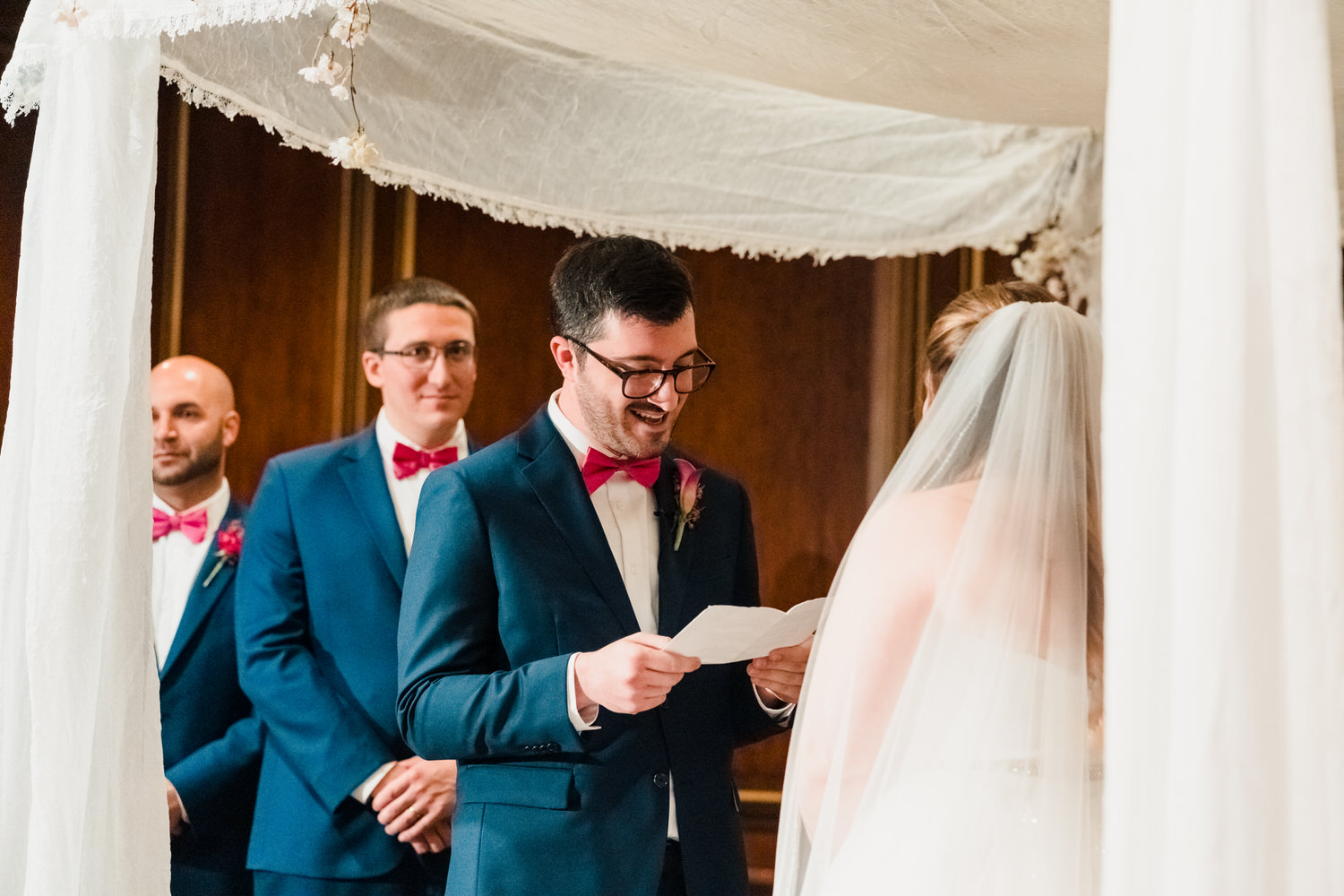 a man in a suit reading a paper to a woman in a wedding dress.